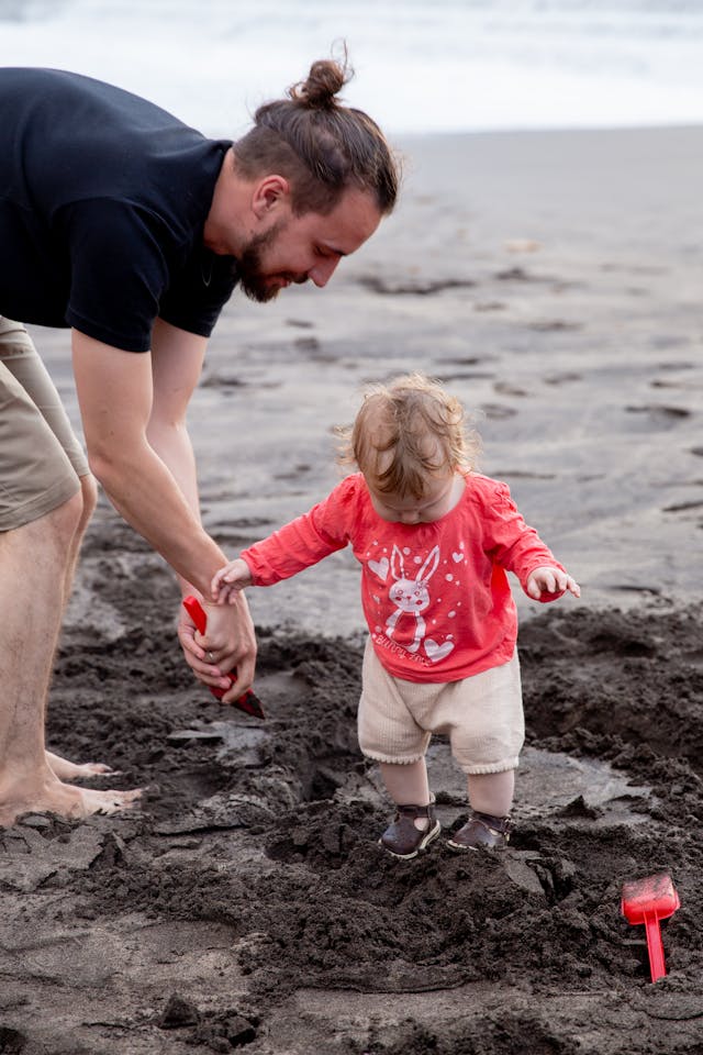 Vater spielt mit kleiner Tochter am Strand im Sand