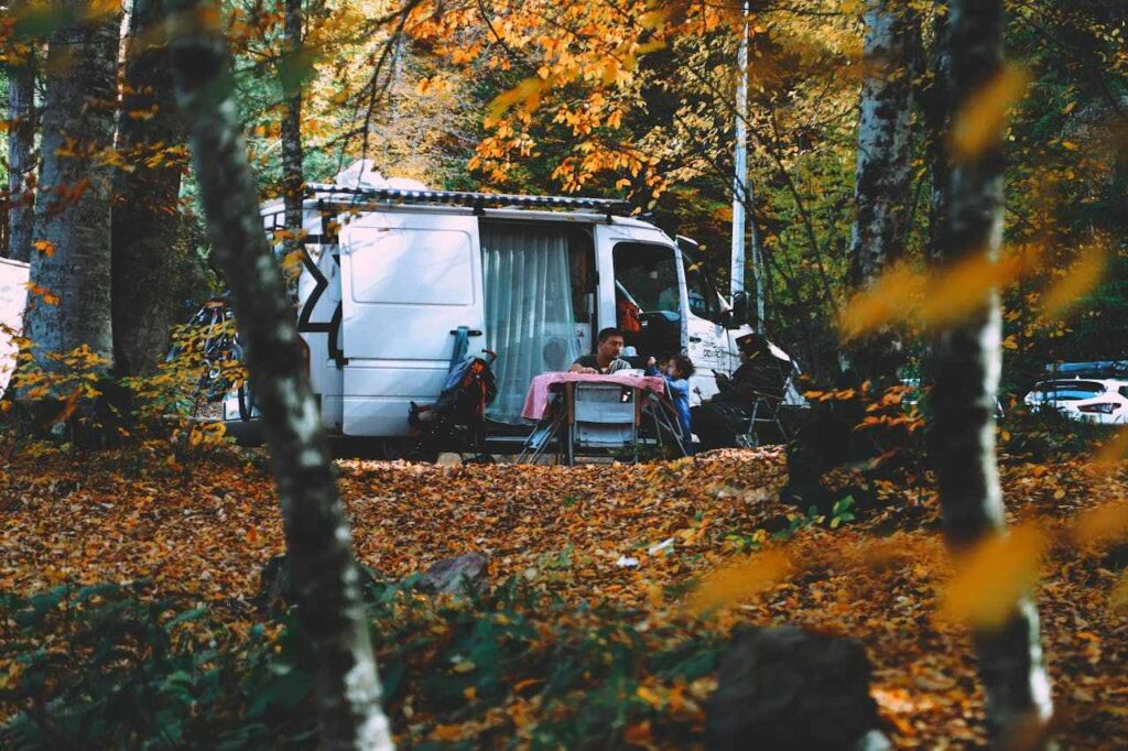 Wohnmobil mit Familie im Wald im Herbst und Piknik am Campingtisch