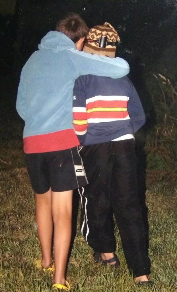 Zwei Kinder gehen zusammen, das eine Kind hat den Arm über die Schulter des anderen gelegt